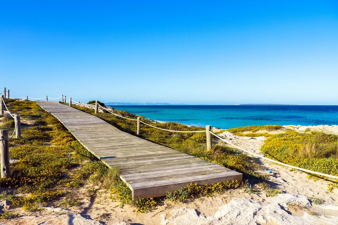 Pier am Strand am türkis blauen Wasser unter klarem Himmel