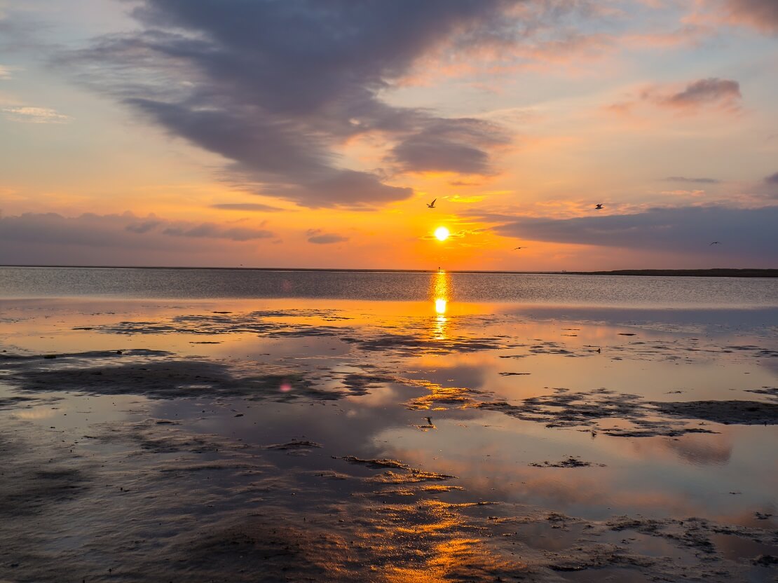 Der Sonnenuntergang vor Wolken und dem Meer