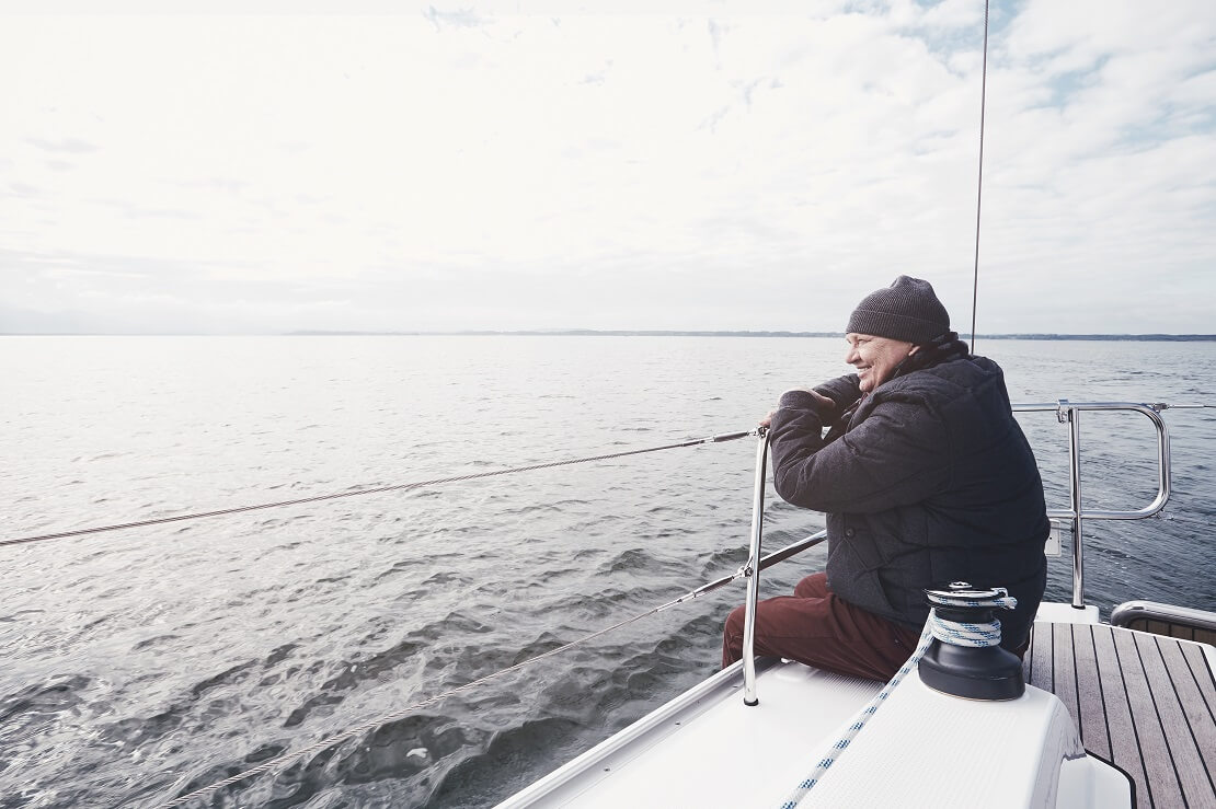 Mann sitzt auf einem Boot und schaut auf das Meer