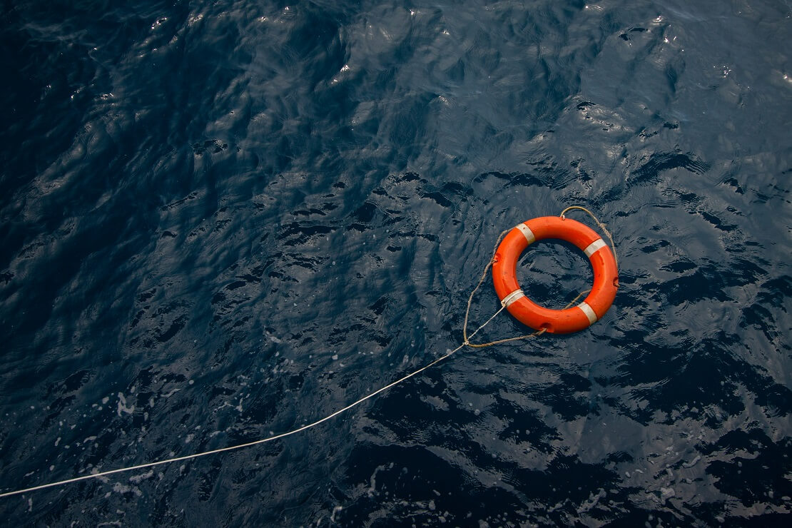 Ein Rettungsring schwimmt im Wasser an einem Seil befestigt