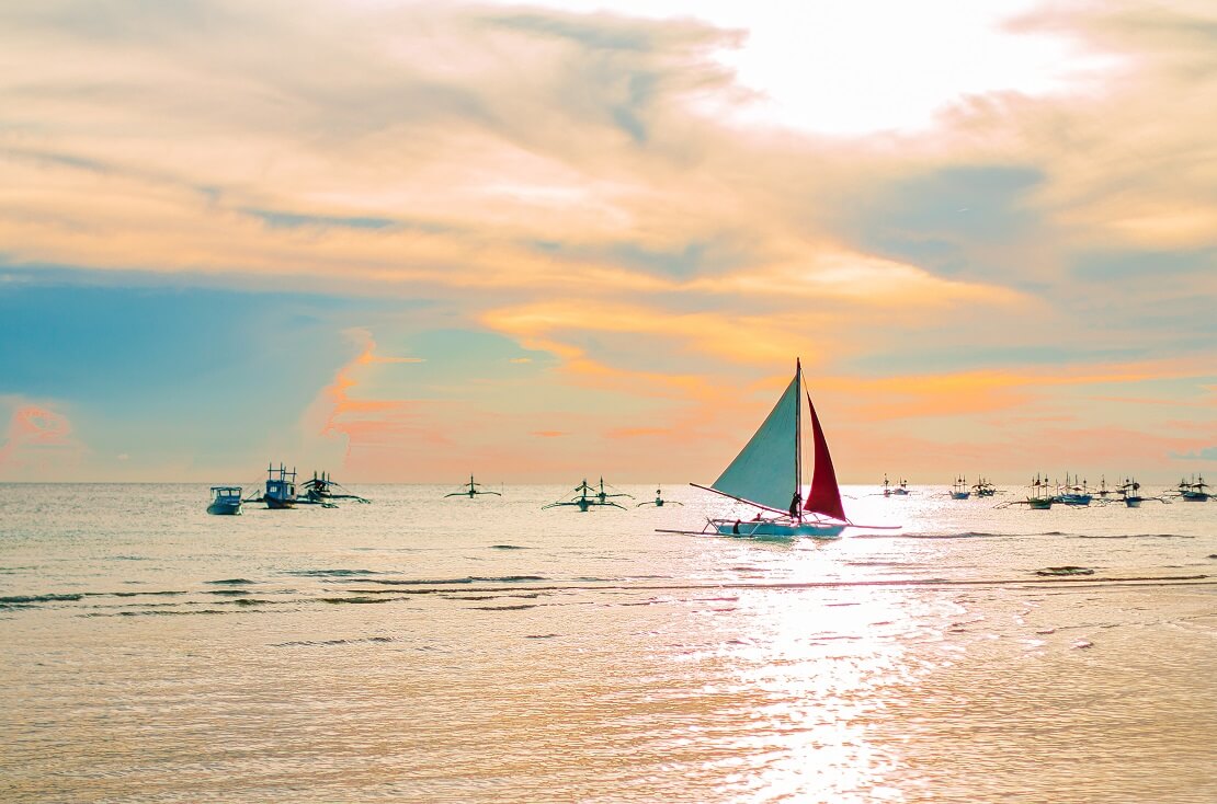 Boote segeln auf dem Meer bei Sonnenuntergang