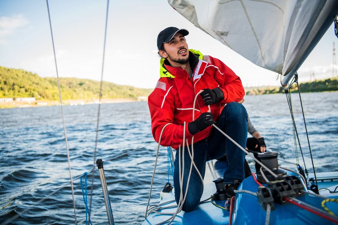 Mann auf einem Boot im Wasser zieht an einem Seil