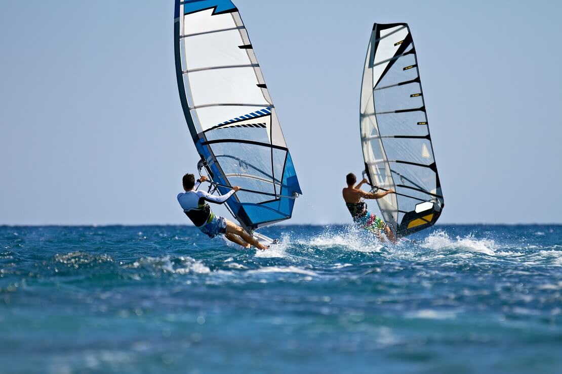 Zwei Windsurfer auf dem blauen Meer