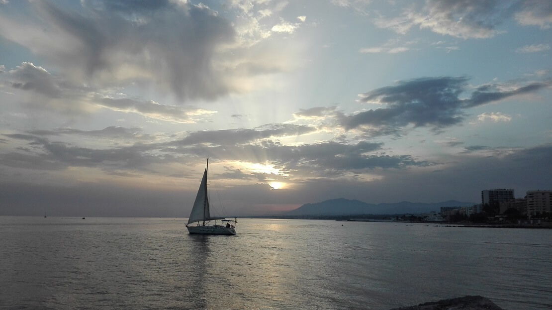 Segelboot bei Sonnenuntergang und Wolken