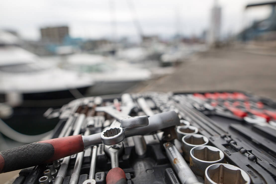 Werkzeuge an einem Hafen vor Segelbooten