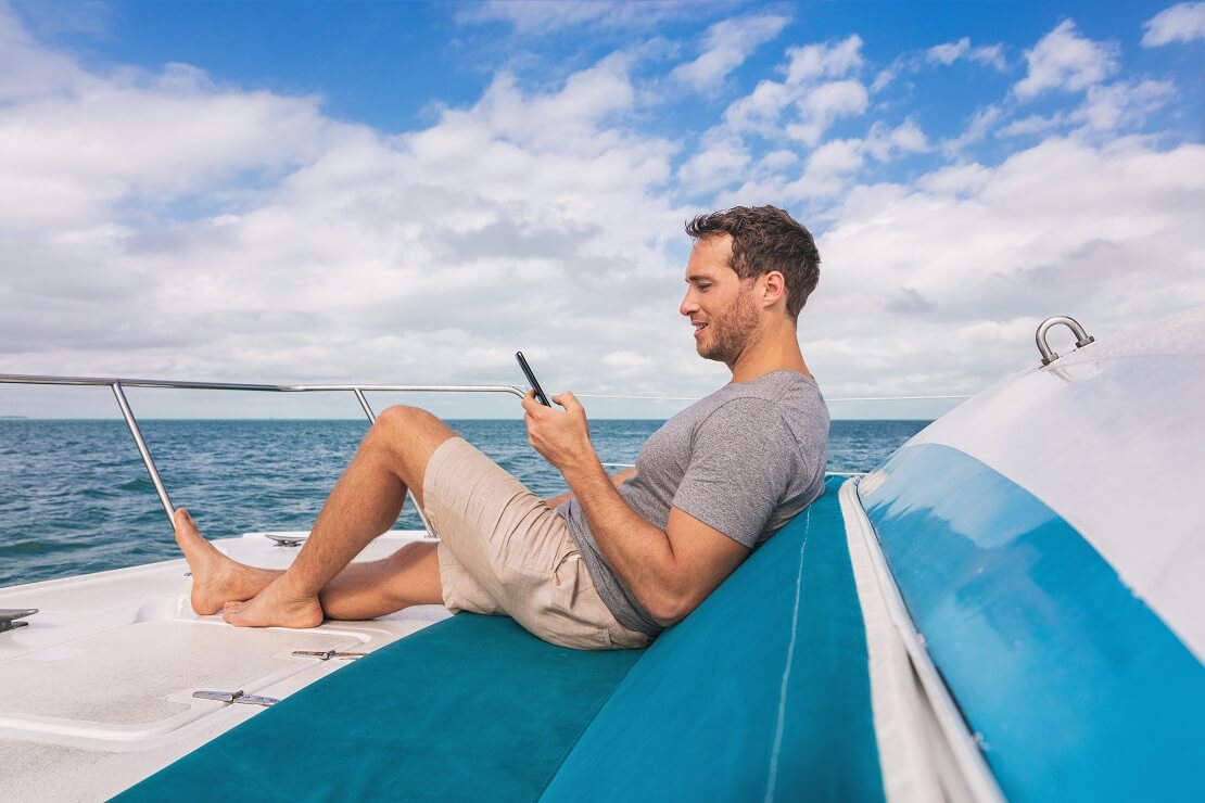 Segler auf einem Boot mit einem Handy in der Hand