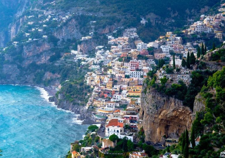 Segeln an der Amalfiküste vor pastellfarbenen Häusern im Felsen